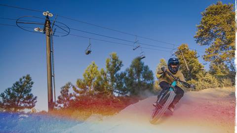Mountain bike rider in full face helmet and goggles riding at Snow Valley Bike Park.