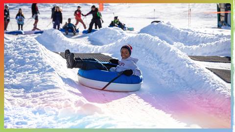 A young adult in a snow tube flying down a tubing lane during the winter time