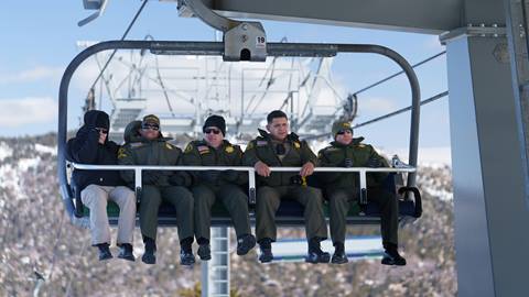 A group of five local sheriffs in uniform riding the chairlift at Snow Valley during winter