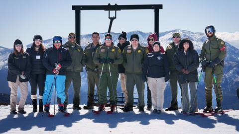 A group of thirteen local sheriffs, some in uniforms and on skis, posing at the top of Chair 1 at Snow Valley