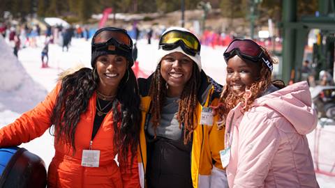 Three adults smiling at the camera while in snow jackets, beanies, and snow goggles at Snow Valley's Coyote Creek Tube Park