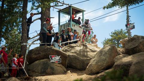 Spectators watch on the sidelines as a mountain bike rider rolls through a rock garden section of the Southwest Downhill race at Snow Valley.