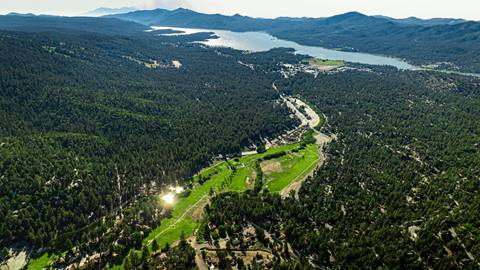 Drone image hovering over Bear Mountain Golf Course and the surrounding Big Bear Lake community with the lake and trees in sight.