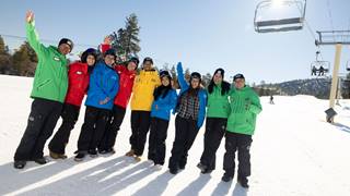 Group of employees for big bear mountain resort standing in the snow posing for a photo