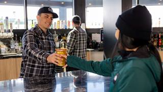 Bartender at Bear Mountain handing a beer off to a guest