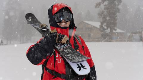 BBMR Ski Patroller on a storm day smiling at the camera holding skis in right arm