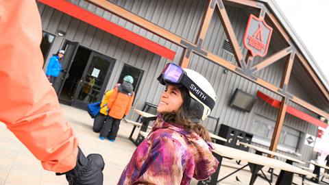 A kiddo in a white helmet looking up at their parent outside of the Adventure Academy 