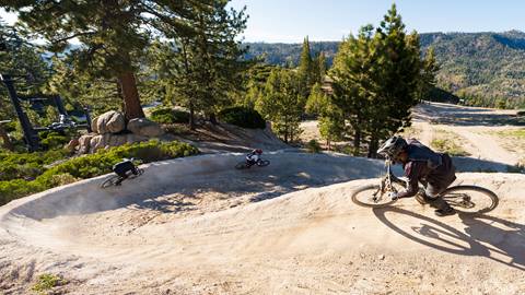 Three mountain bike riders riding through berms at Snow Valley's bike park