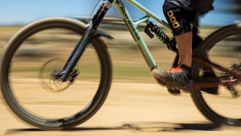 A fast image close up shot of a mountain bikers knees to feet on a green Rocky Mountain branded bike at Snow Summit
