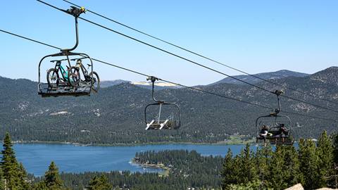 Scenic Sky Chair mountain trees plus lake view with mountain bikes and riders going up to the top of Snow Summit.