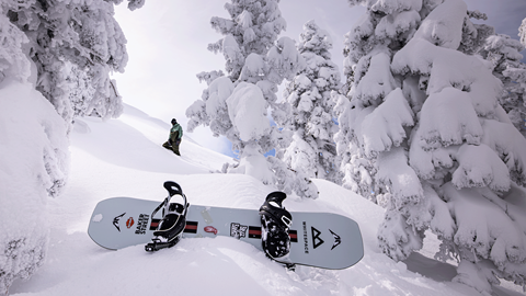 Snowboarder hiking up the snow, leaving his snowboard at the bottom