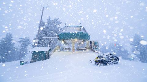 Snow day at the top of a chairlift with a snowmobile in sight