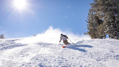 Skier going down the mountain on a sunny day.